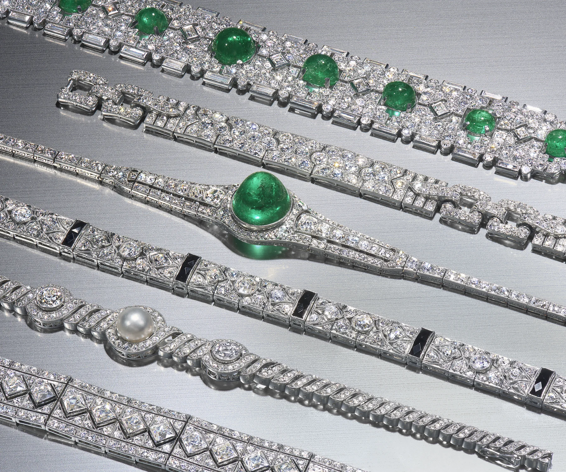 A precise arrangement of important Art Deco diamond, emerald, pearl, and onyx bracelets