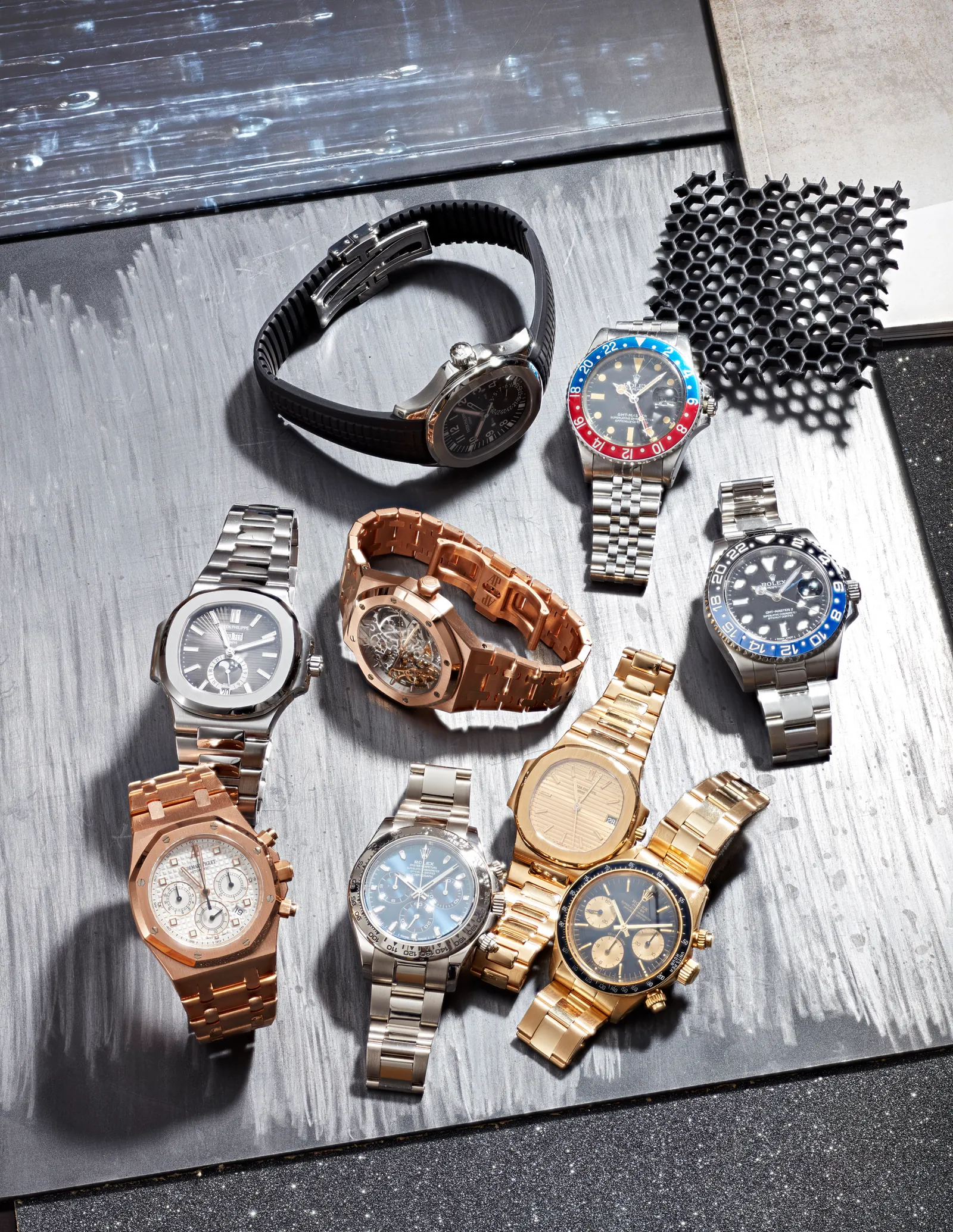 A group of important watches photographed on a cool metal surface
